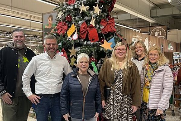 Personen stehen an einem Tisch mit Süßigkeiten und kleinen Spielzeugen